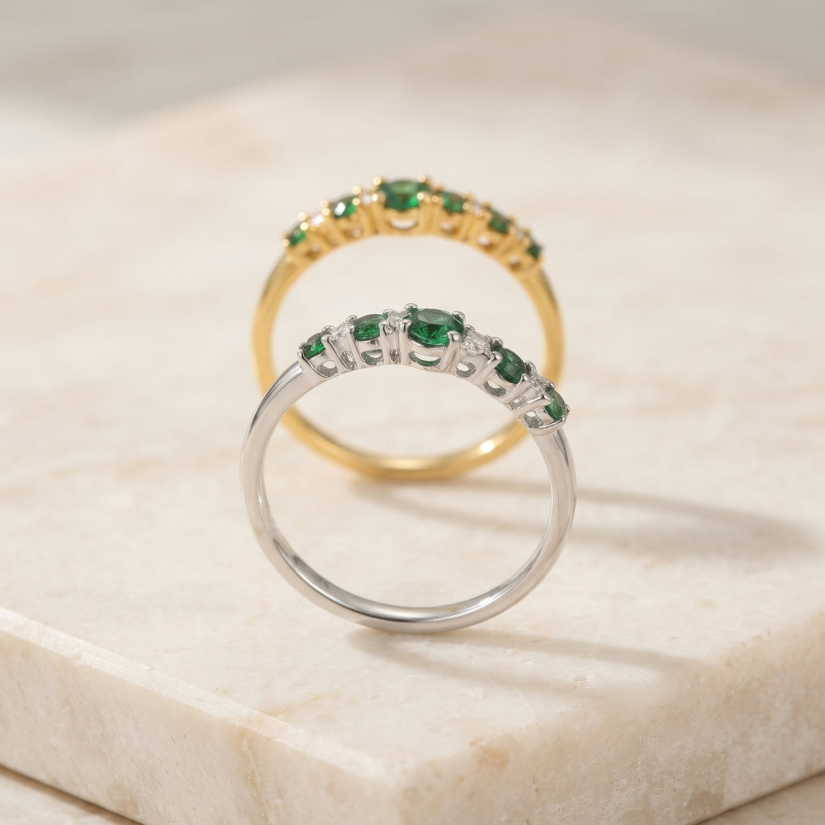 Emerald and diamond graduated five stone rings in 18k white gold and 18k yellow gold