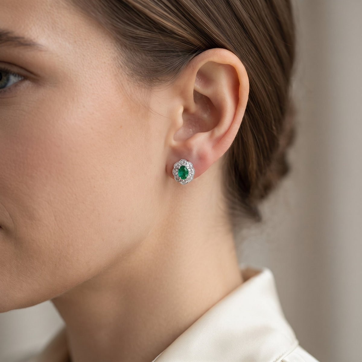 18k white gold oval emerald and diamond milgrain cluster earring worn on the ear