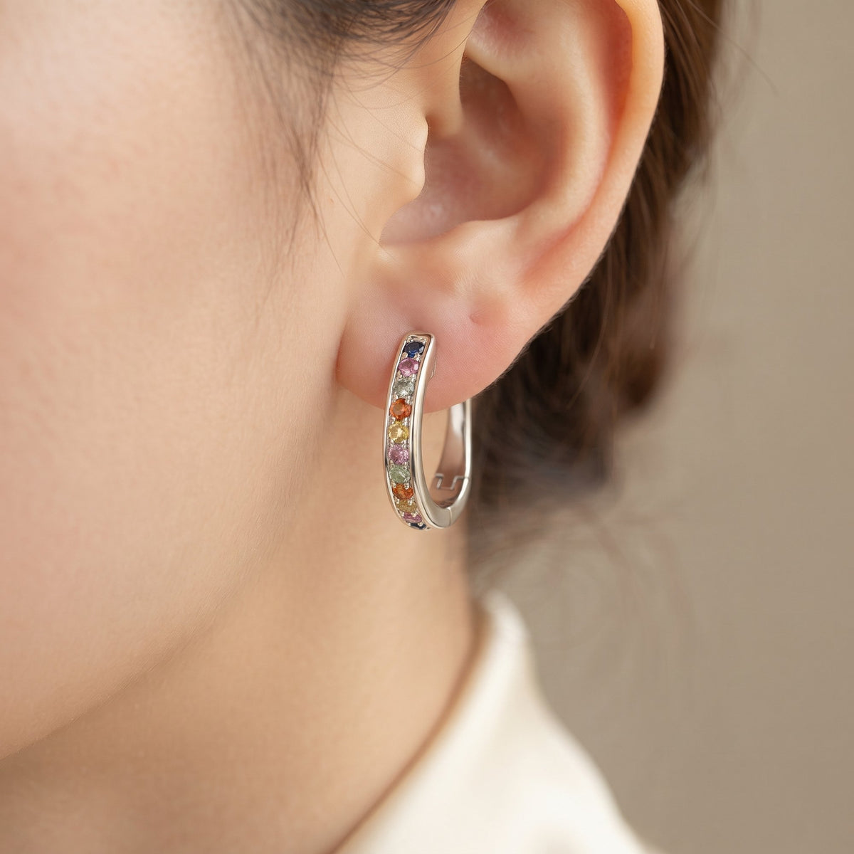18k white gold rainbow sapphire hoop earring worn on the ear