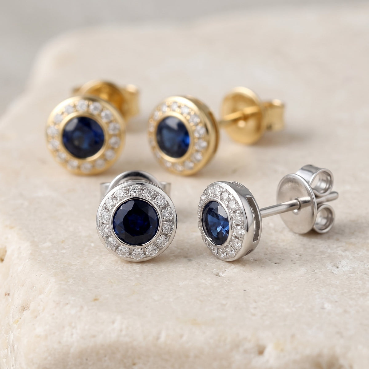 Round sapphire and diamond rubover halo stud earrings in 18k white and yellow gold