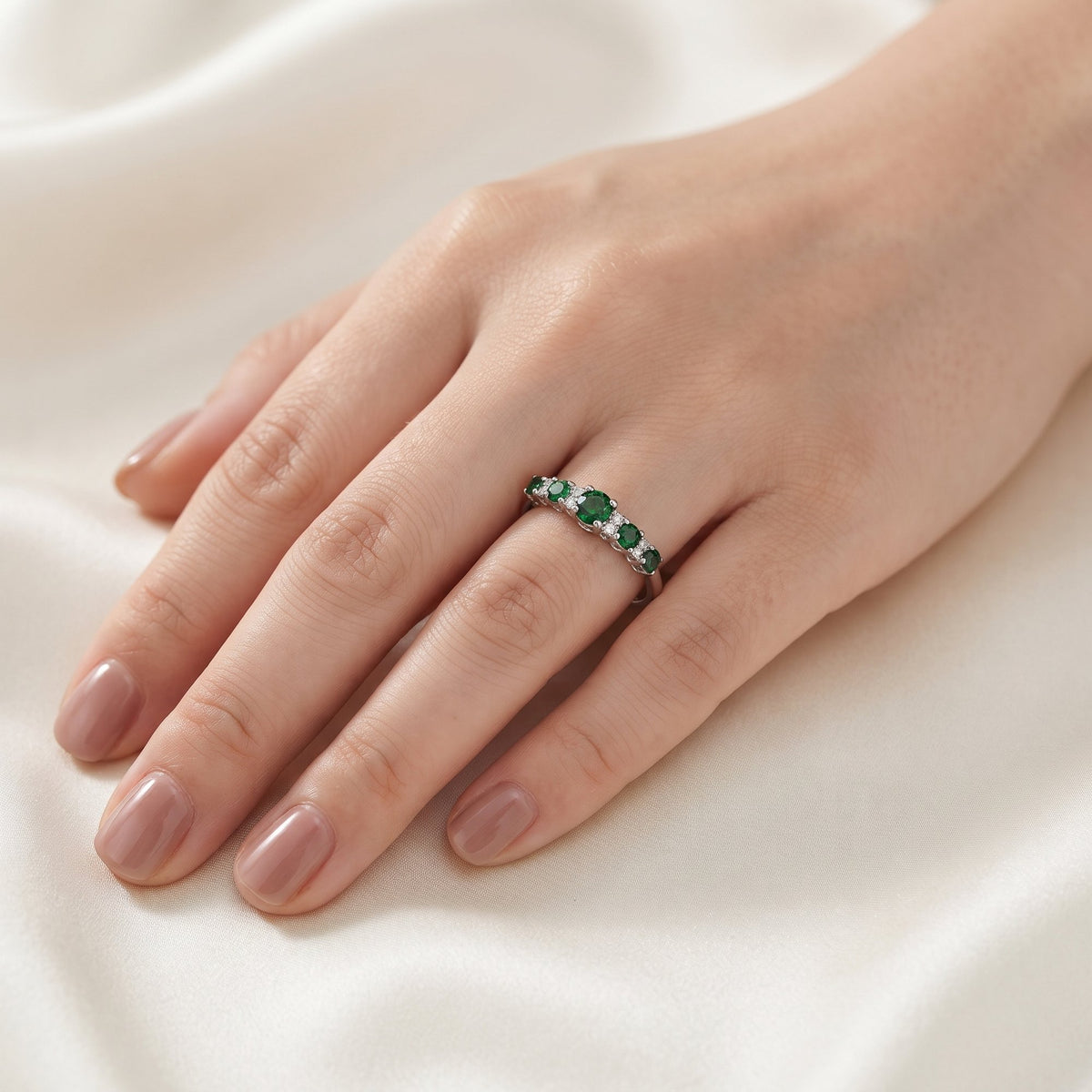 18k white gold emerald and diamond graduated five stone ring worn on the hand