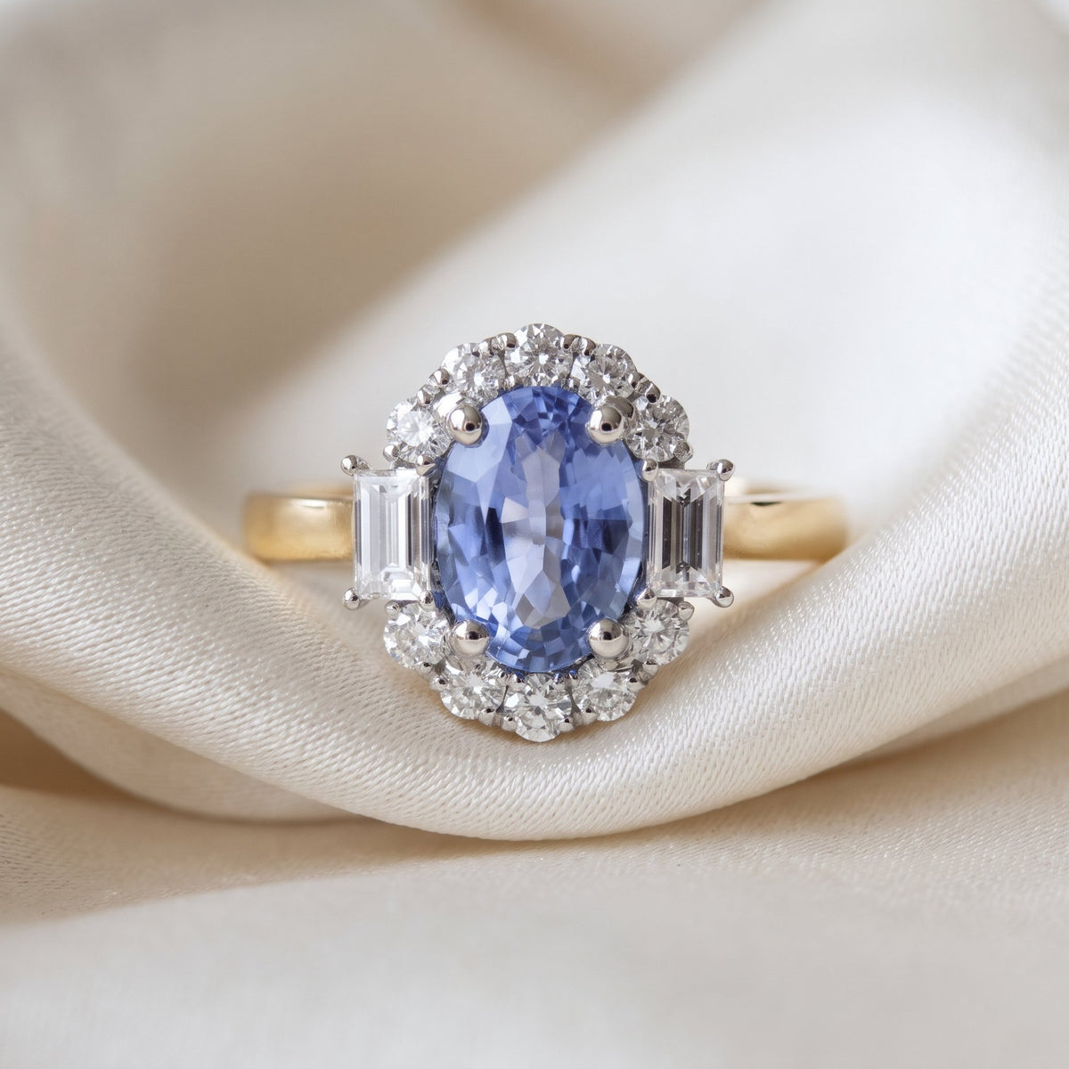 Purple sapphire and diamond oval halo ring in 18k yellow gold and platinum, on ivory silk